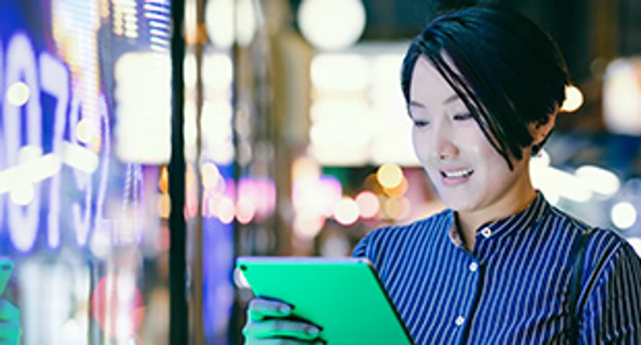 Businesswoman reading her tablet in front of a digital display in Hong Kong