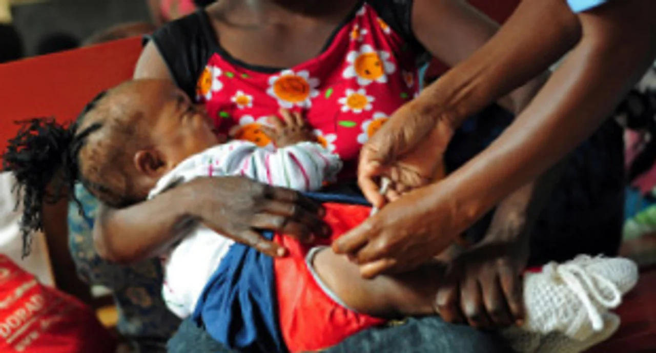 A young woman holding here baby which is being injected with medicine