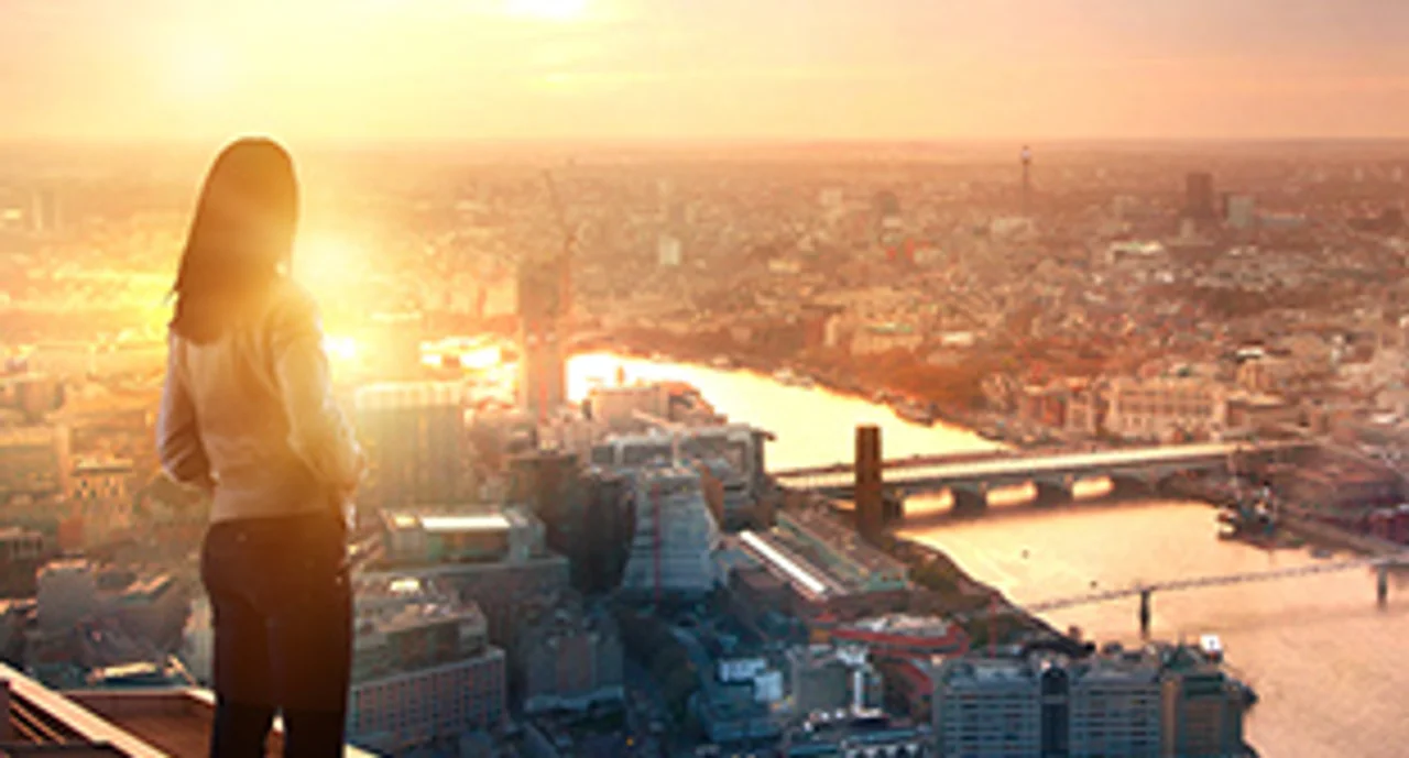 Young woman looking over the city of London at sunset