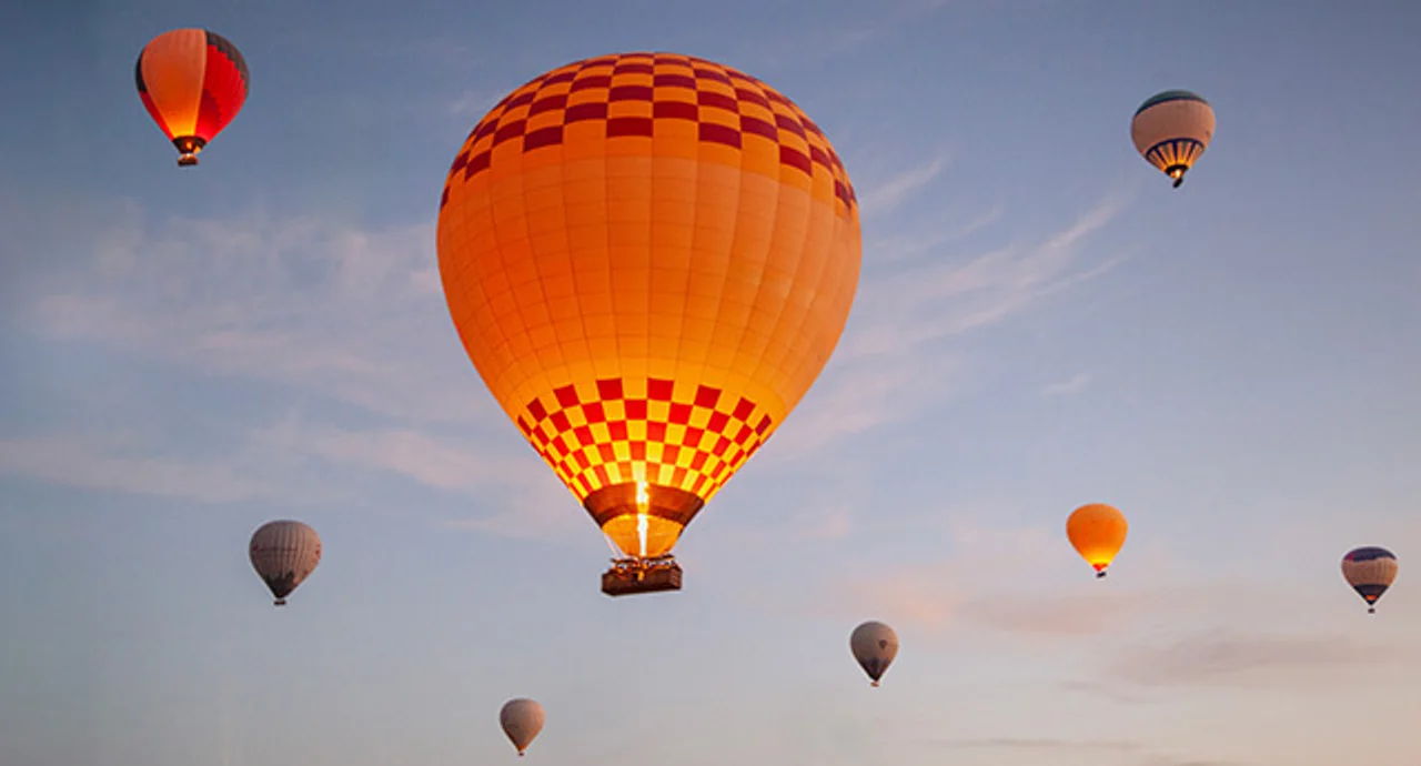 Hot Air Balloons Ascend At Sunrise Over A Scenic Landscape