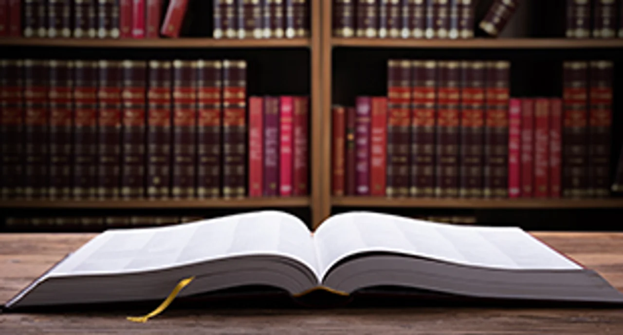 Close-up Of An Open Law Book On Wooden Desk In Courtroom