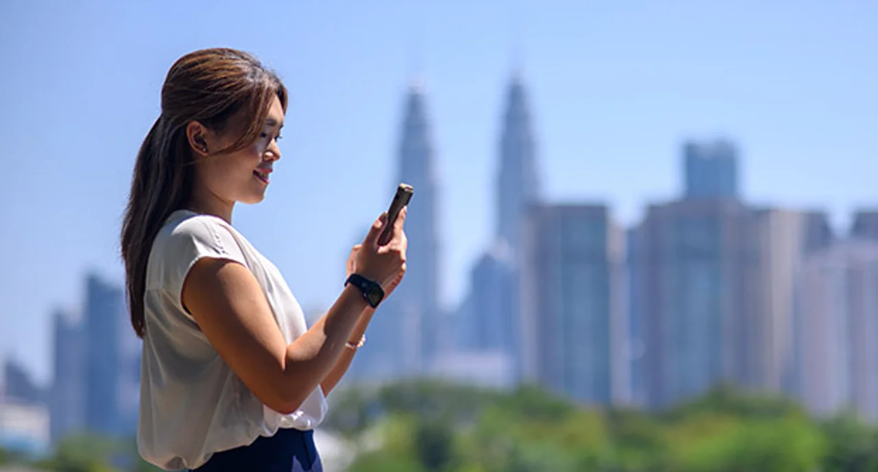 Asian woman holding her phone before a skyline