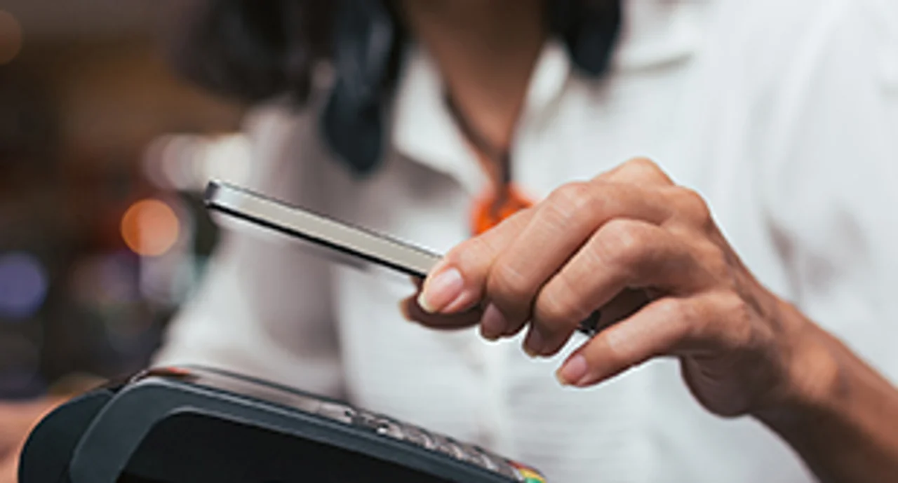Close-up of a woman paying with her smartphone at a card machine