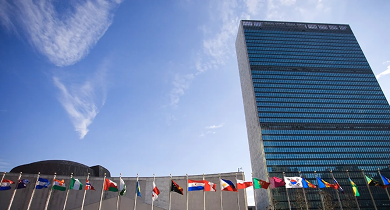 Colorful flags of the world waving in the wind in front of the United Nations building.