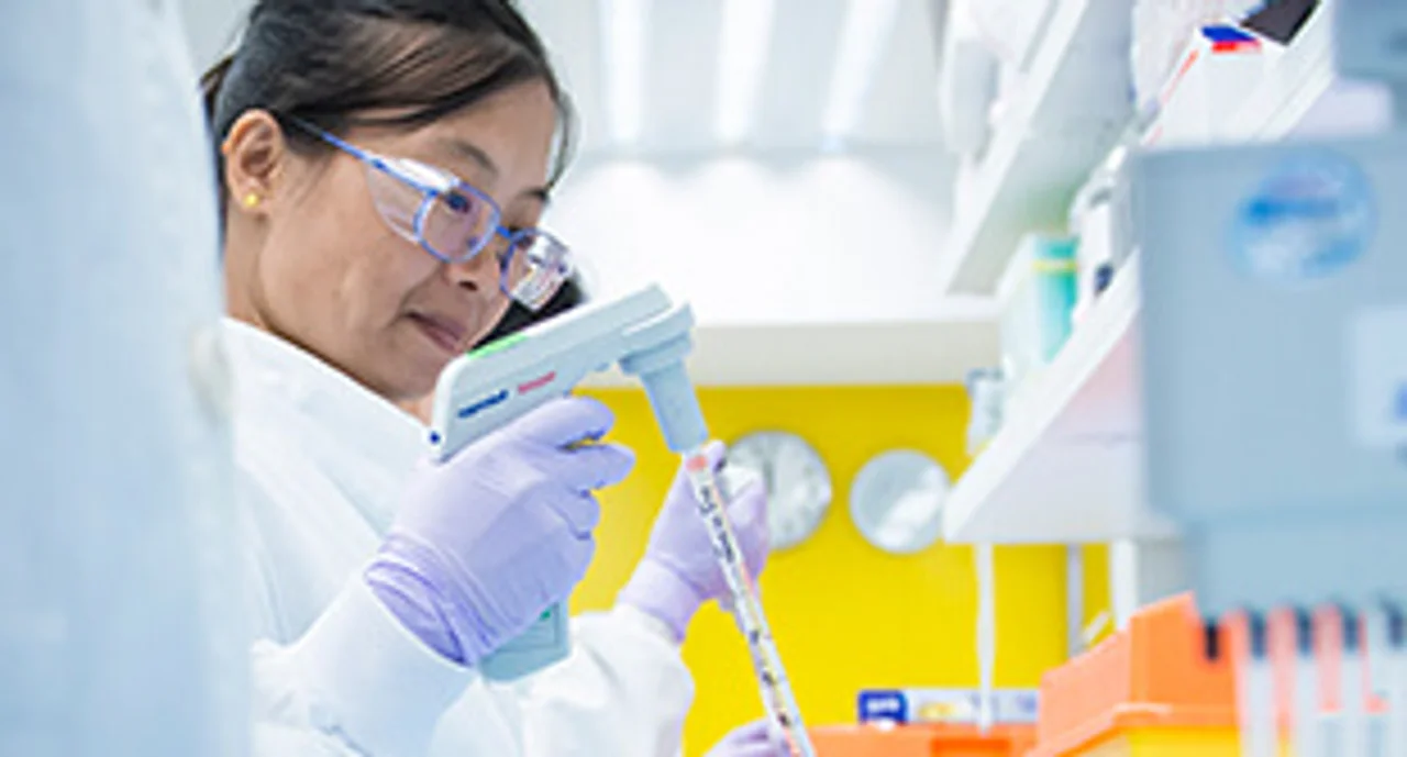 An Asian female laboratory technician very focused on pipetting