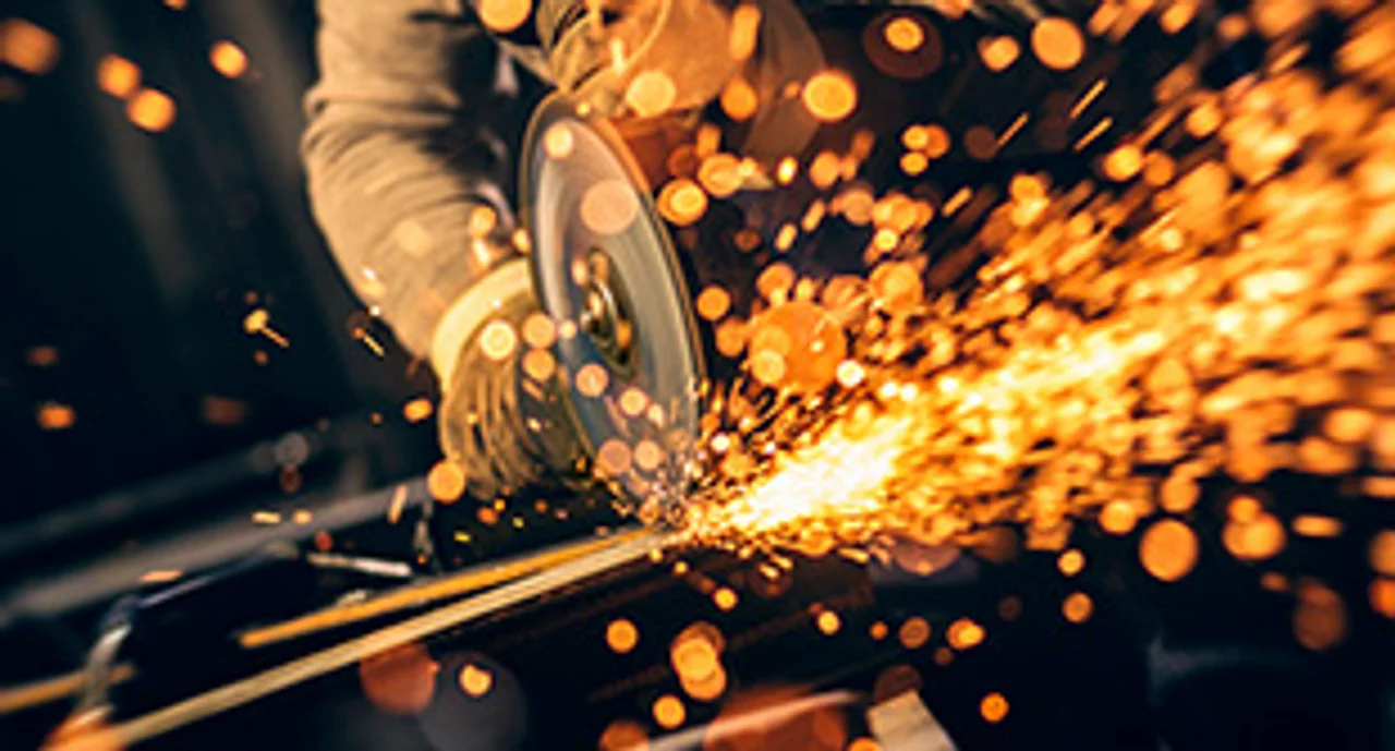 Metal worker cutting a metal objects with circular saw in small workshop